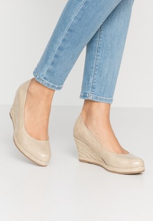 Beżowe buty na koturnie z gładkiej skórzanej cholewki oraz plecionym, teksturowanym obcasem z juty. Okrągły czubek i subtelny połysk.