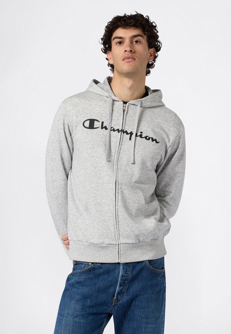 Sudadera con capucha gris con cremallera hecha de tela suave, con un gran logo negro de "Champion" en el pecho y capucha ajustable con cordón.