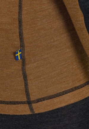 Brown and dark gray fabric with visible stitching. A small blue and yellow flag tag is attached to the hem. Textured surface.