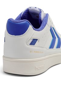 Biały skórzany sneaker z niebieskimi akcentami, teksturowanym obcasem i siateczkową podszewką. Złoty napis "ST. POWER PLAY" i gumowa podeszwa.