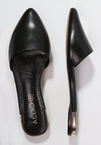 Svarta lädermules med spetsig tå och slip-on-design, med en slät yta och en gyllene detalj på klacken.