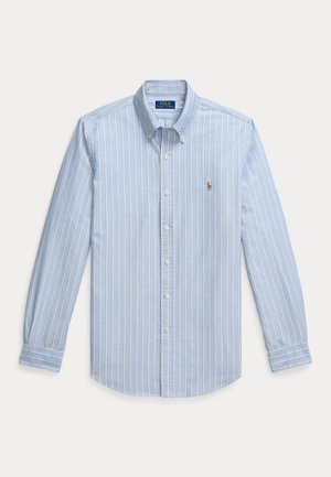 Chemise bleu clair à manches longues et boutonnée, avec de fines rayures verticales blanches et un petit logo brodé sur la poitrine.