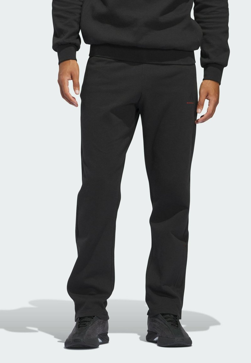 Zwarte sweatpants met een lose pasvorm, gemaakt van zacht materiaal. Voorzien van een elastische tailleband en een minimale rode logo-accent op het been.