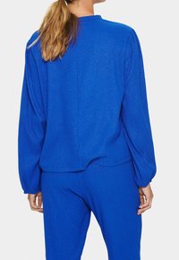 Top blu textured con maniche lunghe e gonfie e scollatura rotonda, abbinato a pantaloni blu textured coordinati.