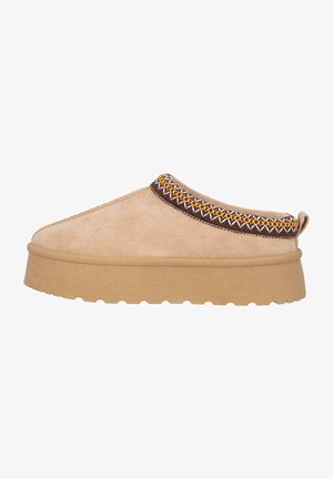 Beige slip-on sko med tekstureret stof, en tyk tan sål, og dekorativ brun og gul syning omkring kraven.