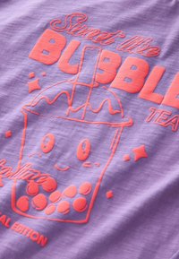 Lilla kangas, millel on mänguline graafika koralli värvi bubble tea tassist, millel on naeratav nägu, mullid ja tekst "Magus nagu BUBBLE TEA."