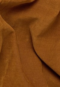 Tessuto texturizzato di un caldo arancione bruciato. Presenta una fine rigatura e una superficie liscia, che mette in evidenza sottili variazioni di luce e ombra.