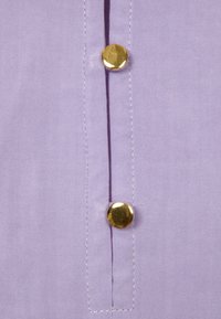 Lavender fabric shirt with a placket featuring three gold buttons. Smooth texture with neat stitching along the edges.