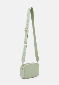 Pravokotni crossbody nahrbtnik iz svetlo zelene sintetične tkanine, z označeno naramnico in zlatimi kovinskimi akcenti. Gladka tekstura z zadrgo.