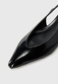 Pump in vernice nera con punta appuntita, lati aperti e finitura liscia. Presenta una silhouette elegante e senza hardware visibile.