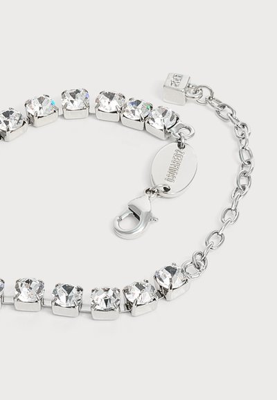 Bracelet en argent avec des pierres précieuses carrées et transparentes, un fermoir mousqueton et une étiquette ovale gravée sur une chaîne ajustable.