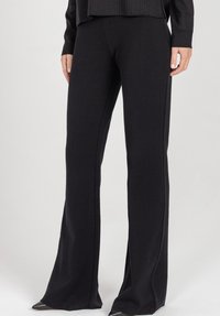 Czarne rozszerzane spodnie z miękkiego materiału. Posiadaj�ą przeszycia wzdłuż szwów, tworząc gładką sylwetkę.