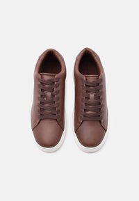 Καφέ δερμάτινα αθλητικά παπούτσια με λείο φινίρισμα, που διαθέτουν καφέ κορδόνια, λευκές ελαστικές σόλες και μινιμαλιστικό σχεδιασμό.