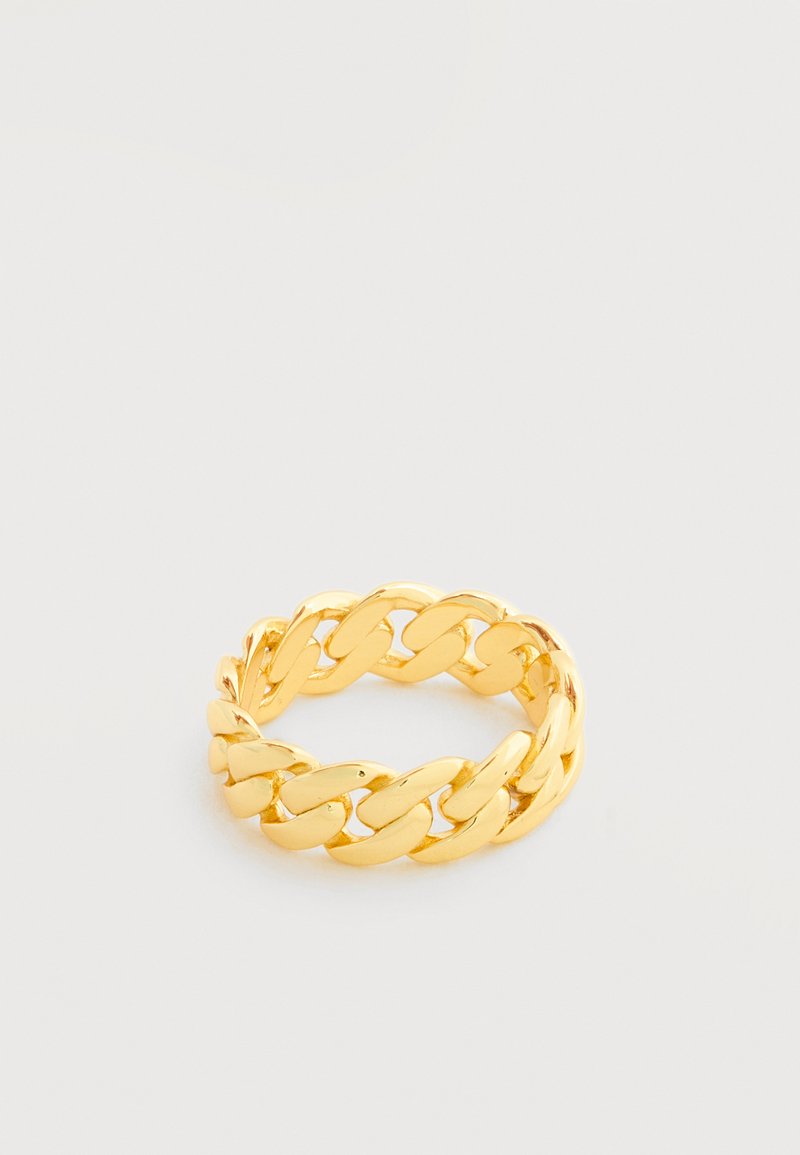 Χρυσό δαχτυλίδι με συνδεδεμένους κρίκους, που ακουμπά σε λευκή επιφάνεια, με χοντρές, ενωμένες καμπυλωτές συνδέσεις και γυαλιστερό φινίρισμα.