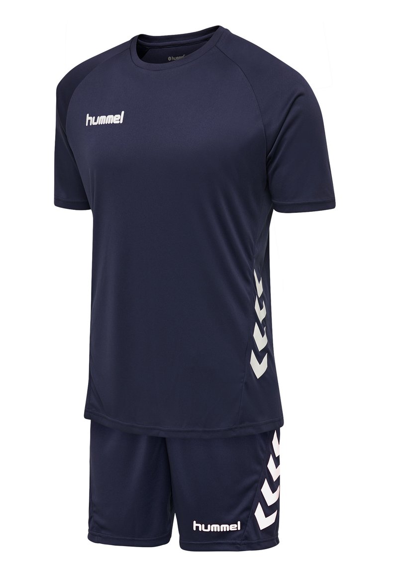 Mørkeblå sportsdragt med korte ærmer og matchende shorts. Har hvidt logo og chevron-mønstre på siderne. Fremstillet af åndbart materiale.