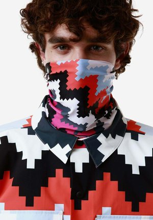 Gaiter multicolore con motivo a zigzag in rosso, nero, rosa e blu. Indossato con una maglietta che presenta un design geometrico a contrasto.