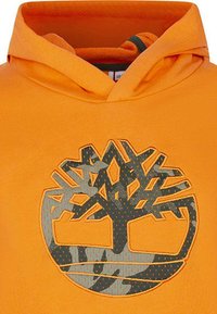 Hoodie orange avec un logo d'arbre gris aux motifs texturés. Le tissu semble lisse, avec une capuche et un col côtelé.