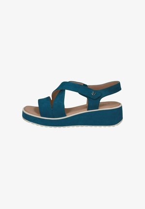 Las sandalias de cuña de ante azul verdoso presentan correas entrelazadas, una correa trasera y una suela blanca contrastante. El diseño enfatiza la comodidad y la estabilidad.