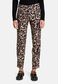 Spodnie w panterkę w beżowo-czarnym kolorze o dopasowanym kroju. Posiadają zapięcie na guzik i kieszenie. Połączone z czarnymi butami z złotymi akcentami.