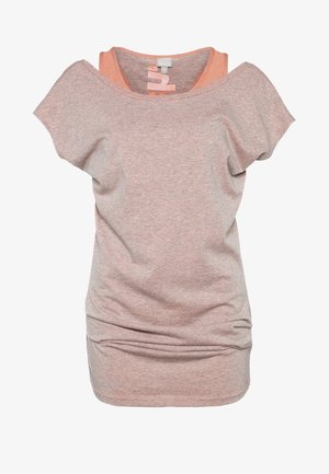 Graues T-Shirt mit kurzen Ärmeln und einem etwas längeren Rücken, kombiniert mit dunklen Skinny-Jeans und schwarzen Sportschuhen. Schwarzer Rucksack über der Schulter getragen.