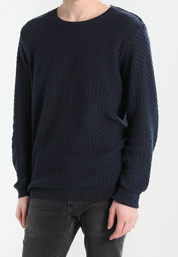 Mörkblå stickad tröja med ribbad textur, rund hals och långa ärmar. Har passande muddar och nederkant för en tät passform.