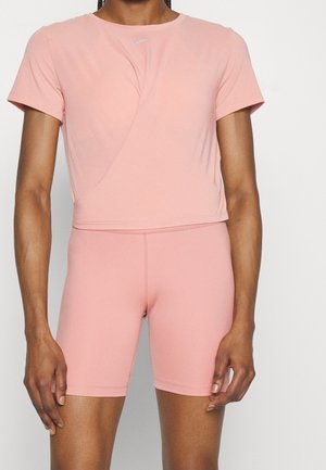 Top atletico rosa con maniche corte e design incrociato, abbinato a pantaloni corti fitted rosa. Tessuto liscio e elastico.
