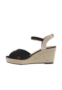 Black wedge sandal featuring a woven jute platform, soft fabric upper, and an adjustable ankle strap made of textured beige material.