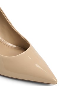 Scarpa in pelle verniciata beige con punta affusolata e scollatura bassa, dalla texture liscia, con una leggera lucidità e una suola sottile.