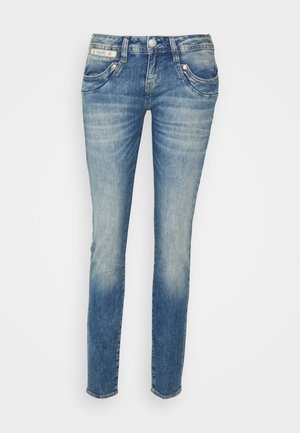 Jean slim bleu délavé avec poches avant, passants pour ceinture et fermeture par bouton, présenté sur un fond blanc uni.