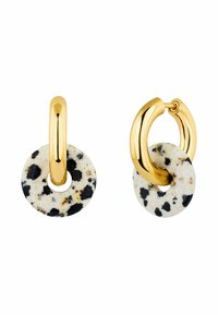 Pendientes de aro de oro con un colgante circular manchado en blanco y negro. El diseño combina materiales metálicos y piedras texturizadas.