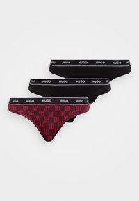 Trois paires de slips Hugo : deux noirs, un rouge avec un motif de logo répété. La ceinture élastique présente des lettres blanches contrastantes.