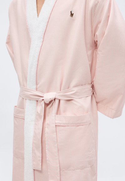 Ρόμπα με ριγέ σχέδιο σε ανοιχτό ροζ και λευκό, με ζώνη δεμένη στη μέση, δύο μπροστινές τσέπες και μικρό κεντητό λογότυπο αλόγου στο στήθος.