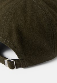 Gorra de béisbol de lana verde oscuro con costuras bordadas y una correa ajustable de hebilla plateada en la parte posterior. Textura suave, forma redondeada.