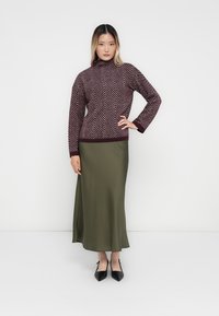 Burgundy patterned knit turtleneck sweater paired with an olive green satin ankle-length skirt and black pointed-toe heels.