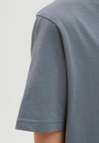 Camiseta de algodón gris con cuello redondo y mangas cortas, con una textura suave y detalles de costura limpios.