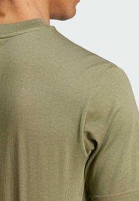 T-shirt verde oliva a maniche corte con scollatura rotonda, realizzato in cotone morbido e testurizzato. Presenta un design semplice e liscio, senza motivi.