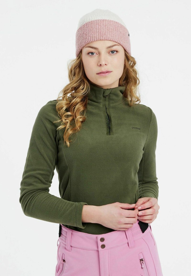 Olivgrüner Fleece-Pullover mit einem halben Reißverschluss am Kragen. Kombiniert mit hellrosa Skihosen. Enganliegendes Design mit langen Ärmeln und dezentem Logodetail.