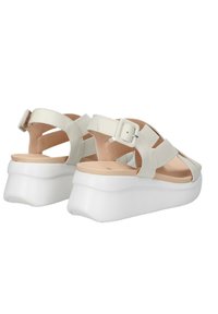 Sandali in pelle bianca con piattaforma, dotati di fibbia regolabile, design open-toe e una base liscia e arrotondata. Le cinghie incrociate aggiungono dettagli.