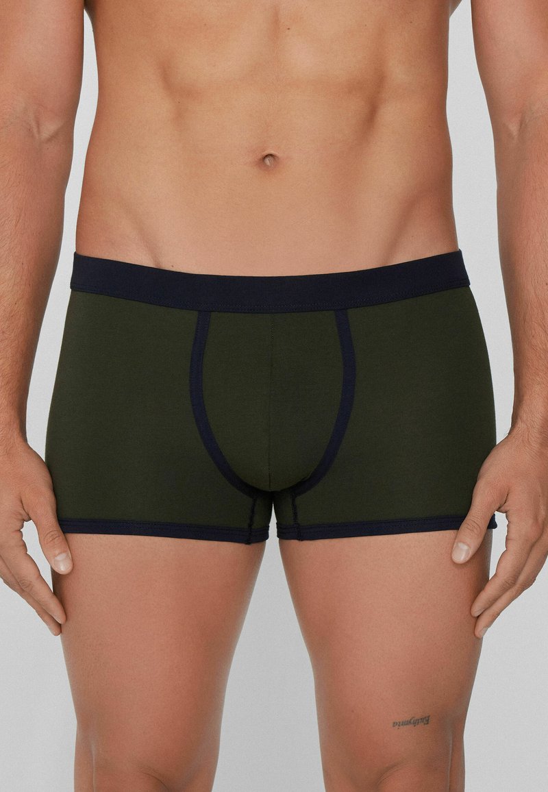 Männer Boxershorts aus dunkelgrünem Stoff mit einem marineblauen Bund. Bieten eine enganliegende Passform, Kontrastnähte und eine Vordertasche zur Unterstützung.