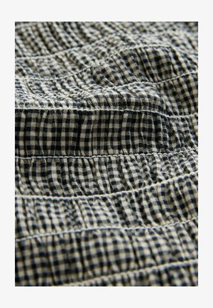 Zils un balts ginghama audums ar savilktu tekstūru, kas izceļ horizontālas šuves un mīkstu, austu izskatu.