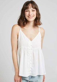 Top blanc sans manches avec un décolleté en V et un boutonnage à l'avant, présentant une coupe ample et une taille froncée, fabriqué à partir d'un tissu léger.