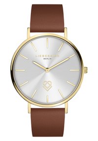Ronde analoge horloge met een zilveren gradient wijzerplaat, gouden markeringen en een bruin leren band. Heeft een logo en een minimalistisch ontwerp.