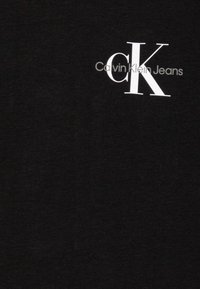 Fekete pamut póló, fehér "CK" logóval és "Calvin Klein Jeans" felirattal. Sima tapintás, kerek nyakú fazon, rövid ujjú.