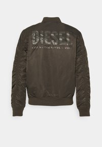 Olivgrön bomberjacka med glänsande svart "DIESEL"-logotyp och text på baksidan. Har ribbad krage och texturerade sidodetaljer.