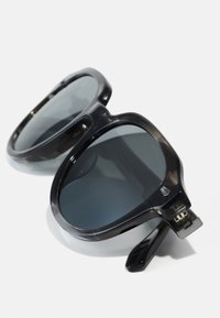 Ochelari de soare negri supradimensionați cu un cadru din plastic lucios, lentile întunecate și un design cu balamale pentru pliere. Accentuati cu elemente metalice.