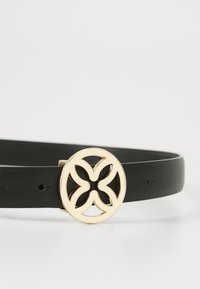 Cintura in pelle nera con una fibbia circolare dorata caratterizzata da un design floreale intagliato. Texture liscia, regolabile con diversi fori.