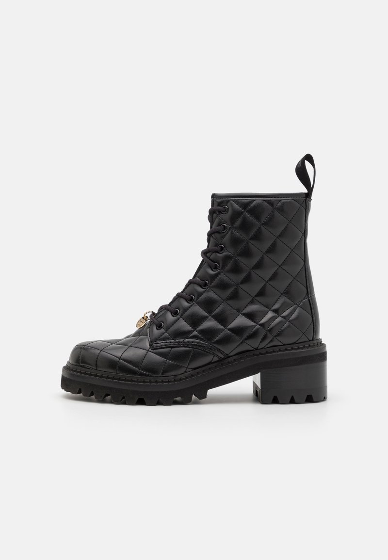 Bottine noire en cuir matelassé avec lacets, talon épais et tirette, sur fond blanc.