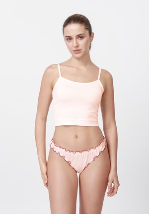 Jasnoróżowy crop top na cienkich ramiączkach o gładkiej fakturze, zestawiony z dopasowanymi bikini z falbankami i czerwonymi akcentami.