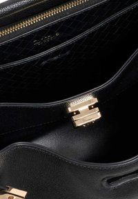 Black leather handbag interior with a golden clasp and zip. Features a quilted pattern and smooth texture. Metallic accents visible.