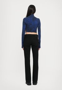 Cropped, long-sleeve top in blue with a textured pattern; paired with black fitted pants and chunky black boots. Plain white background.